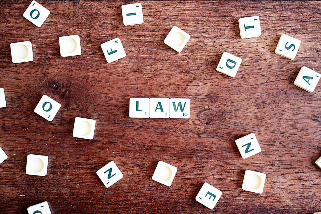 Scrabble Tiles Reading ‘Law’ Surrounded by Other Tiles on A Wooden Surface